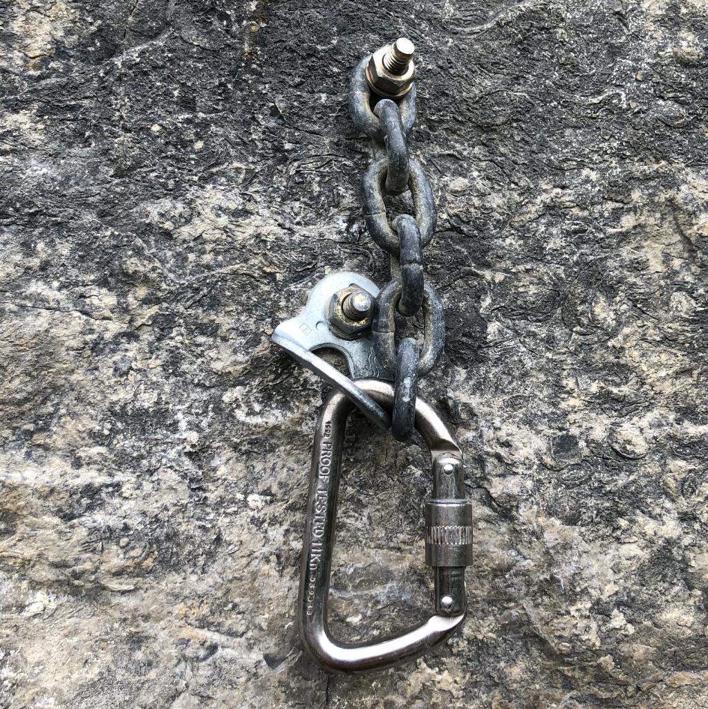 An alloy screwgate hanging on a chain and hanger. The chain has 6 small links and is attached directly to a bolt.