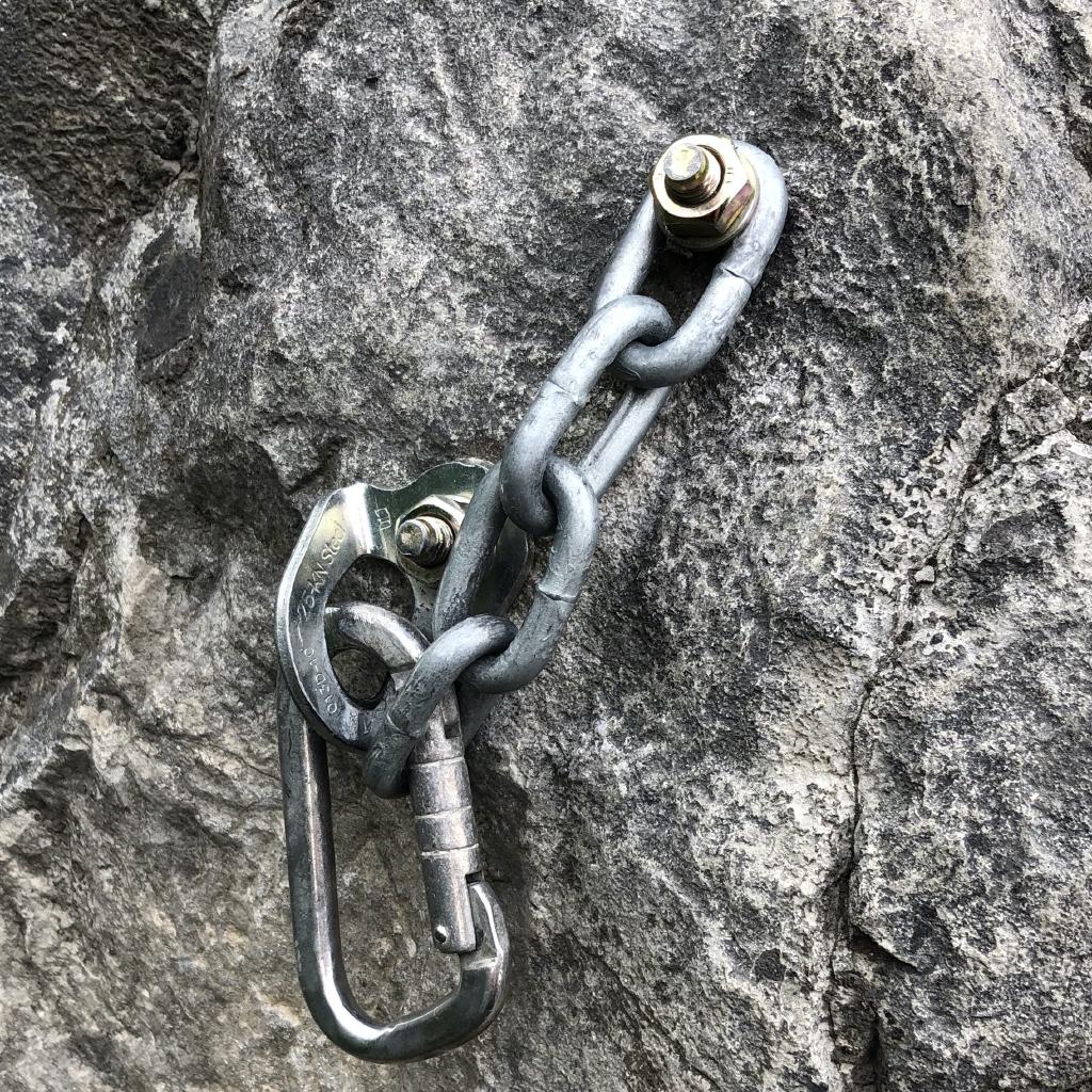 An old snapgate suspended by a chain through a hanger. The chain has 4 short links and is attached directly to a bolt.