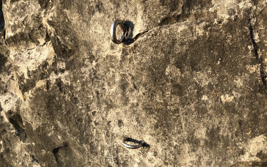 Two resin bolts arranged vertically. The top bolt is vertical (rope in from the sides) and the bottom bolt is horizontal.
