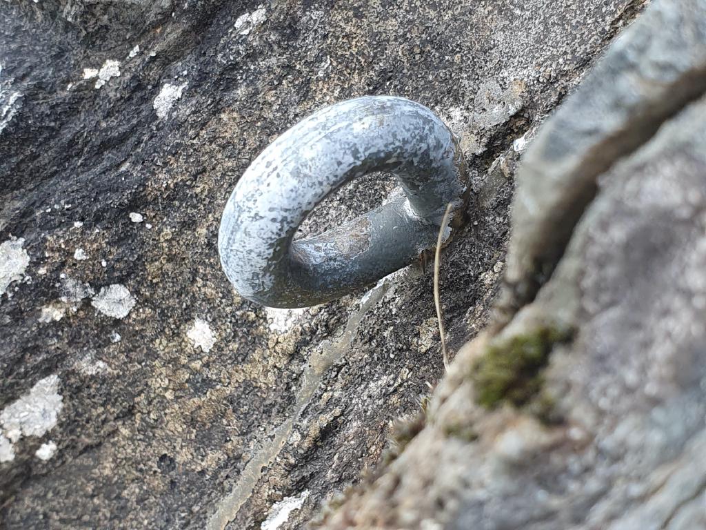 A single resin bolt that has a crack running vertically down the rock where the bolt is placed.