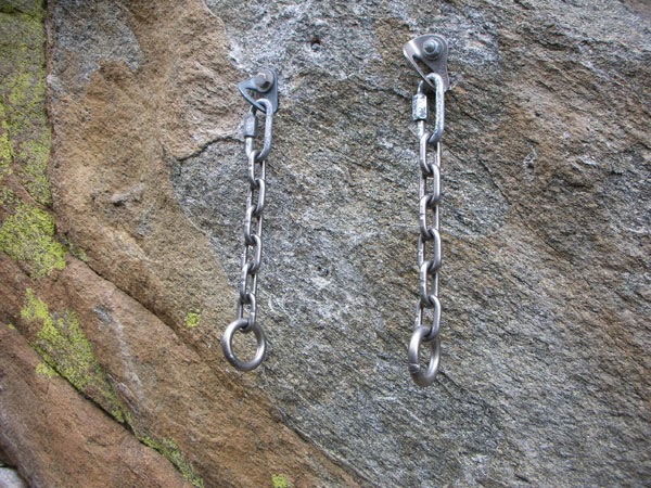 Two sharp hangers with a chain and big ring hanging from each.